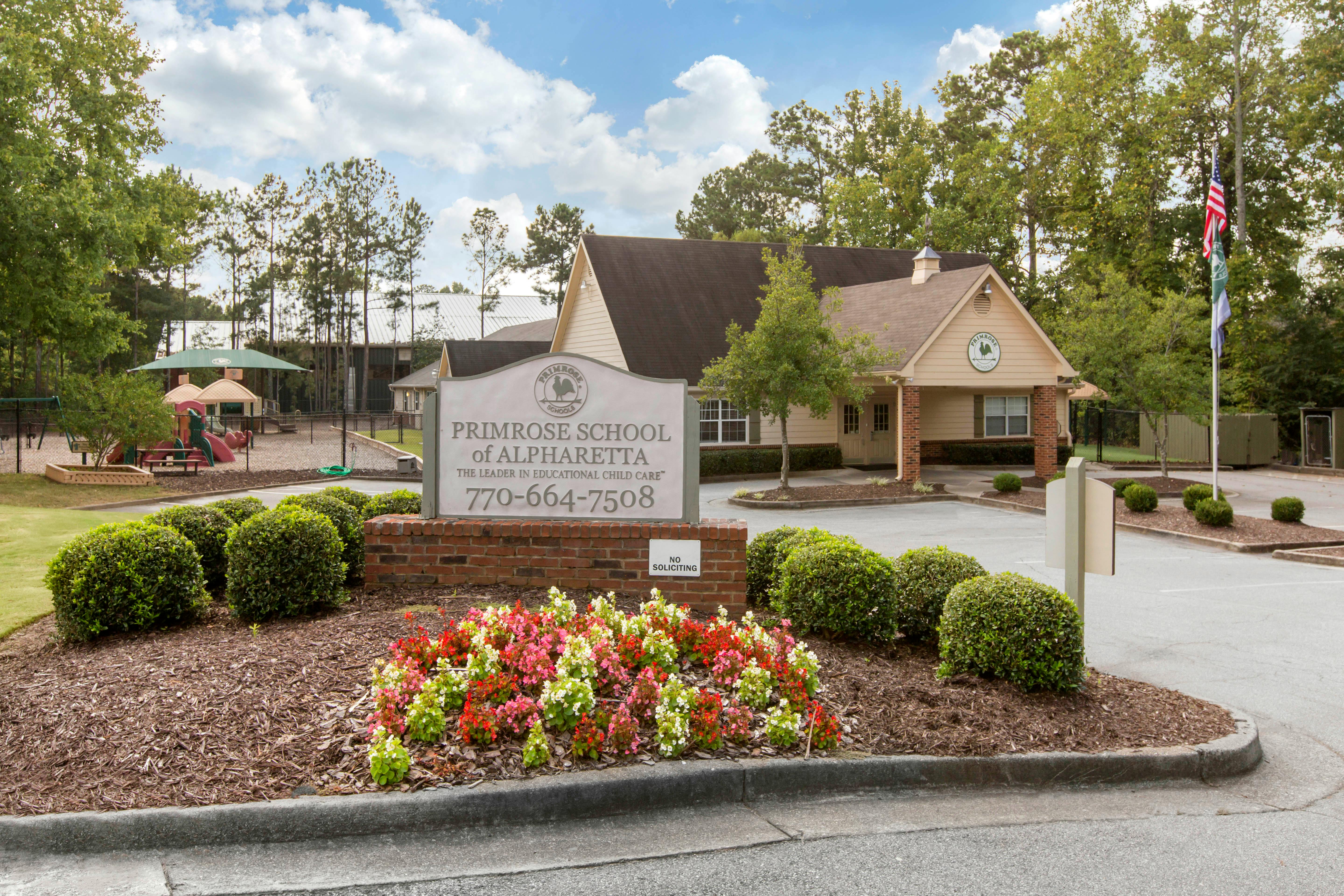Primrose School of Alpharetta sign with phone number, building, and playground
