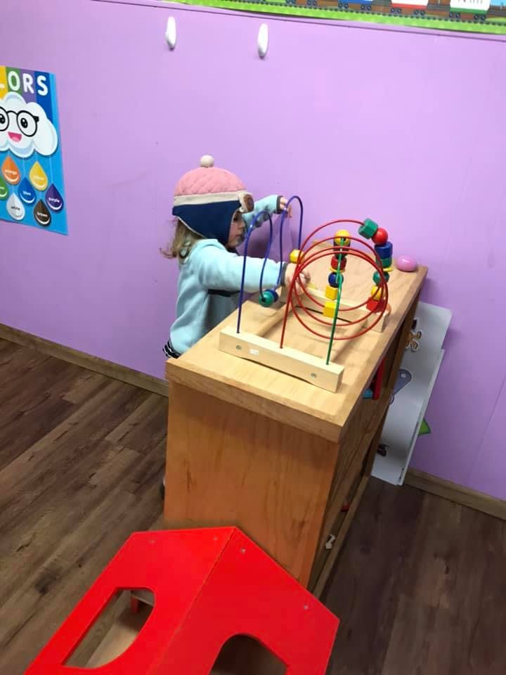 Child playing with a bead maze toy in a classroom
