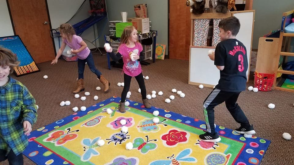 Children playing with white balls on a colorful rug