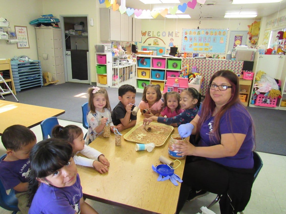 Adult and children sitting at a table in a classroom