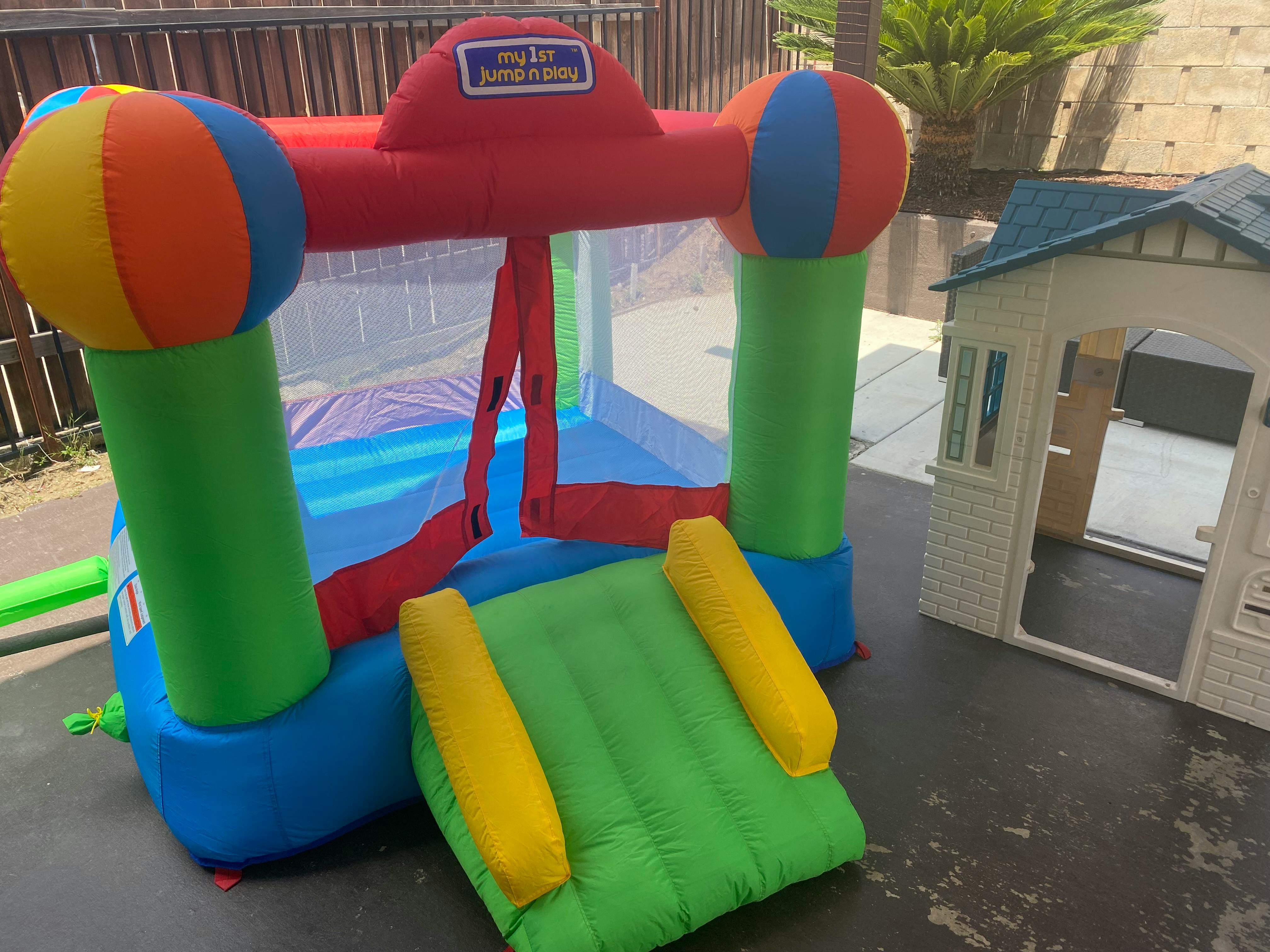 Inflatable bounce house with a slide next to a small playhouse