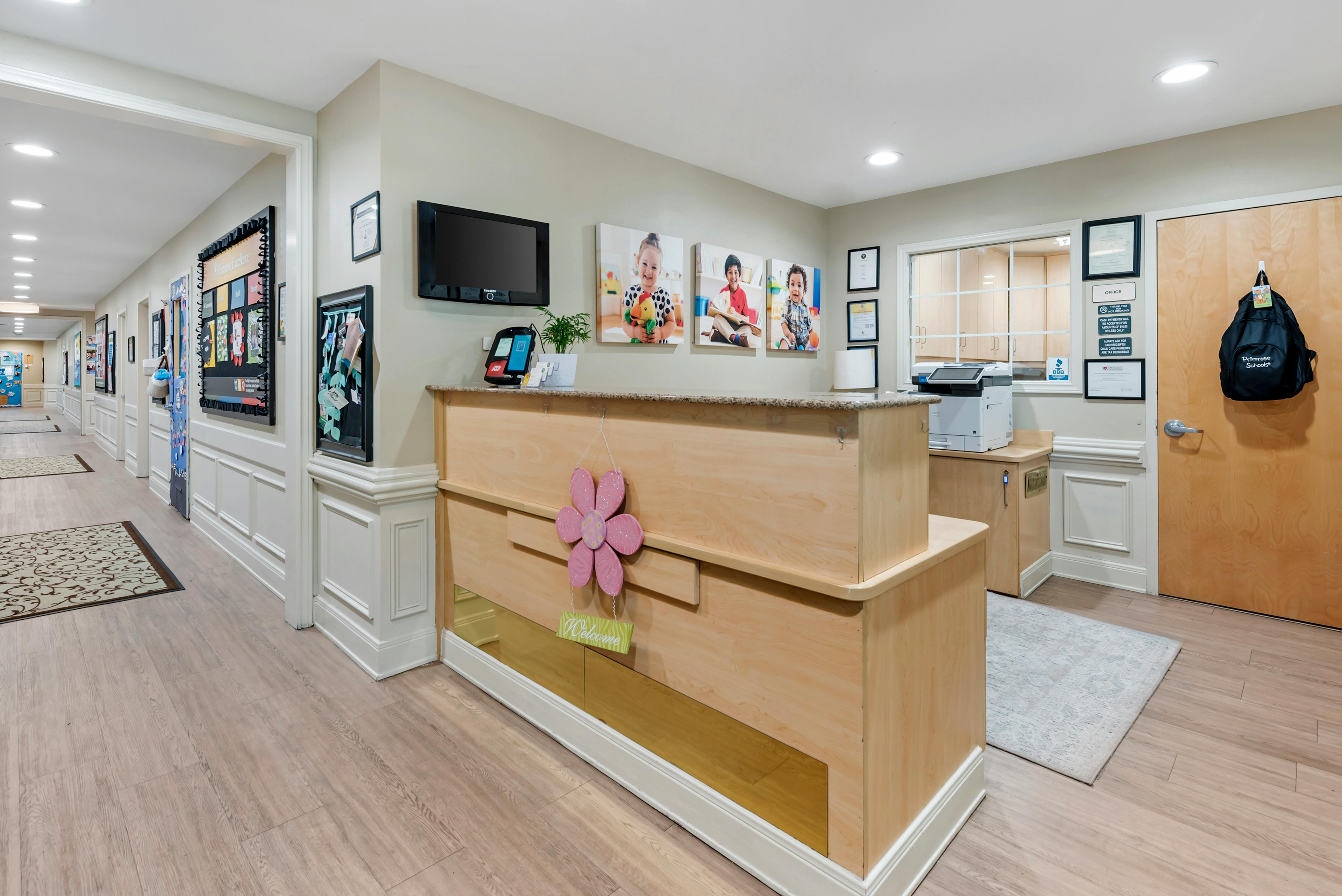 Reception desk with child photos on wall, office window, and hallway