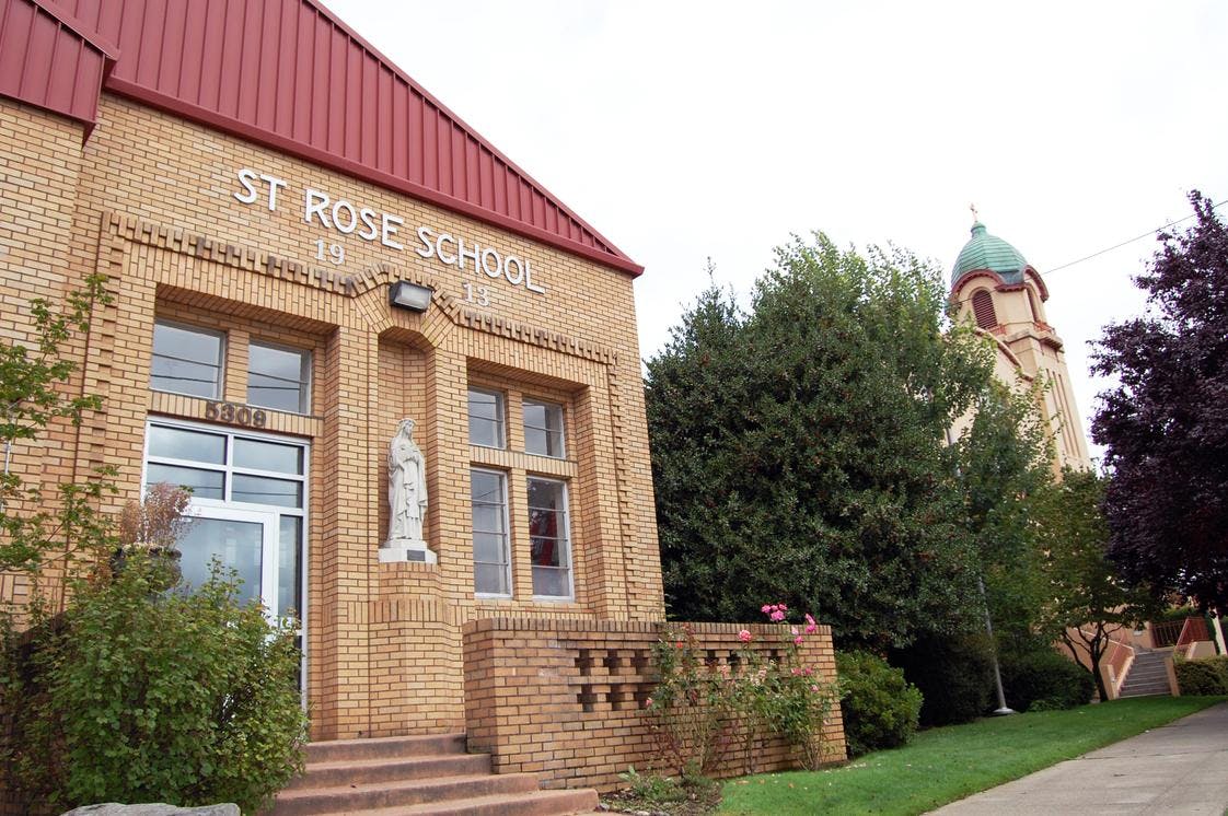 St Rose School building with a statue in a niche and a church tower in background