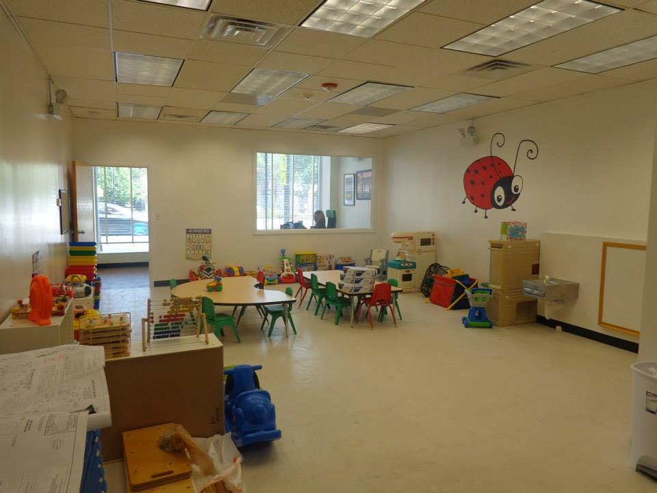 Classroom with small tables and chairs, toys, and a ladybug wall decal