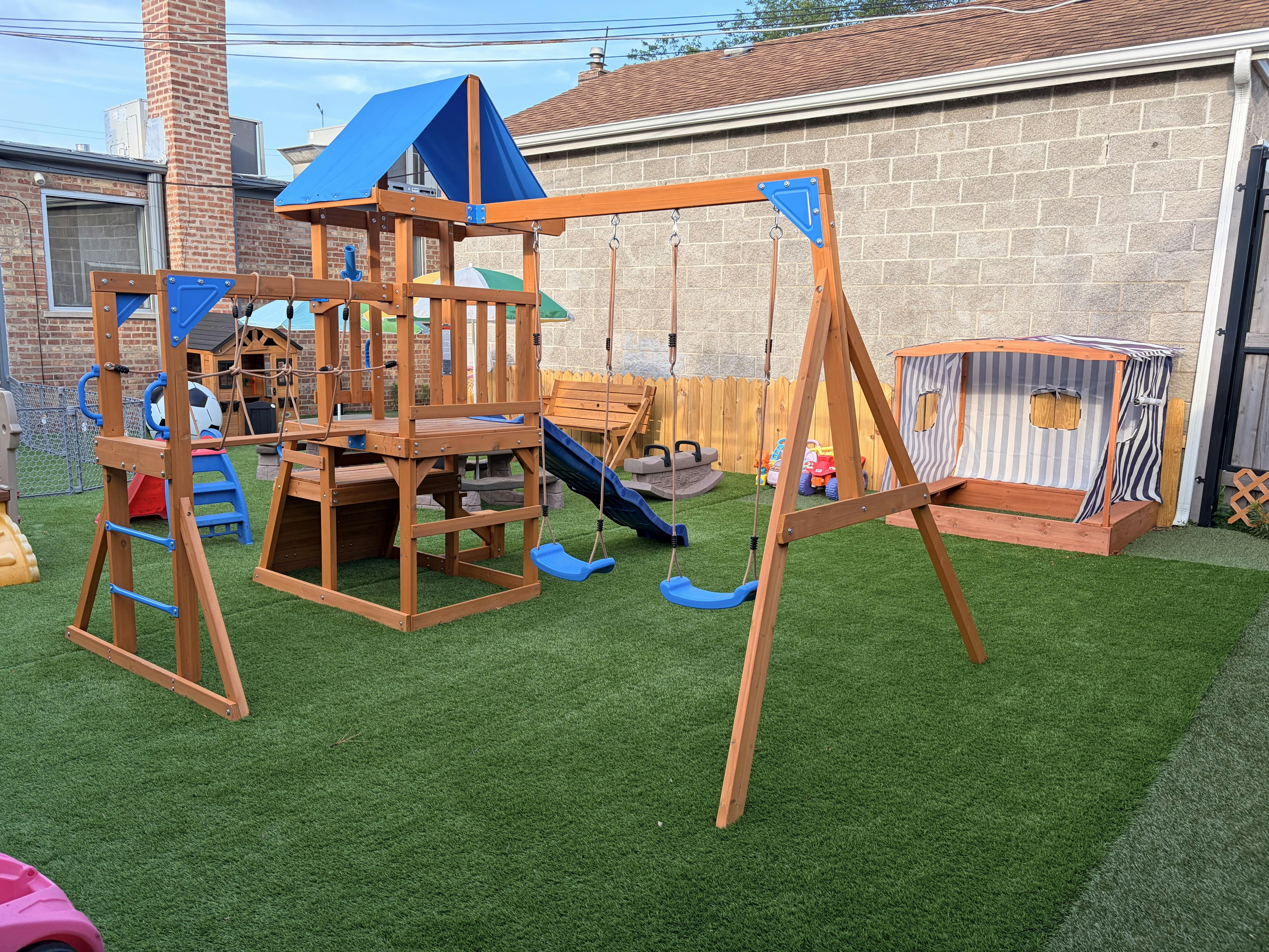 Wooden swing set with slide and climbing features on an artificial turf yard