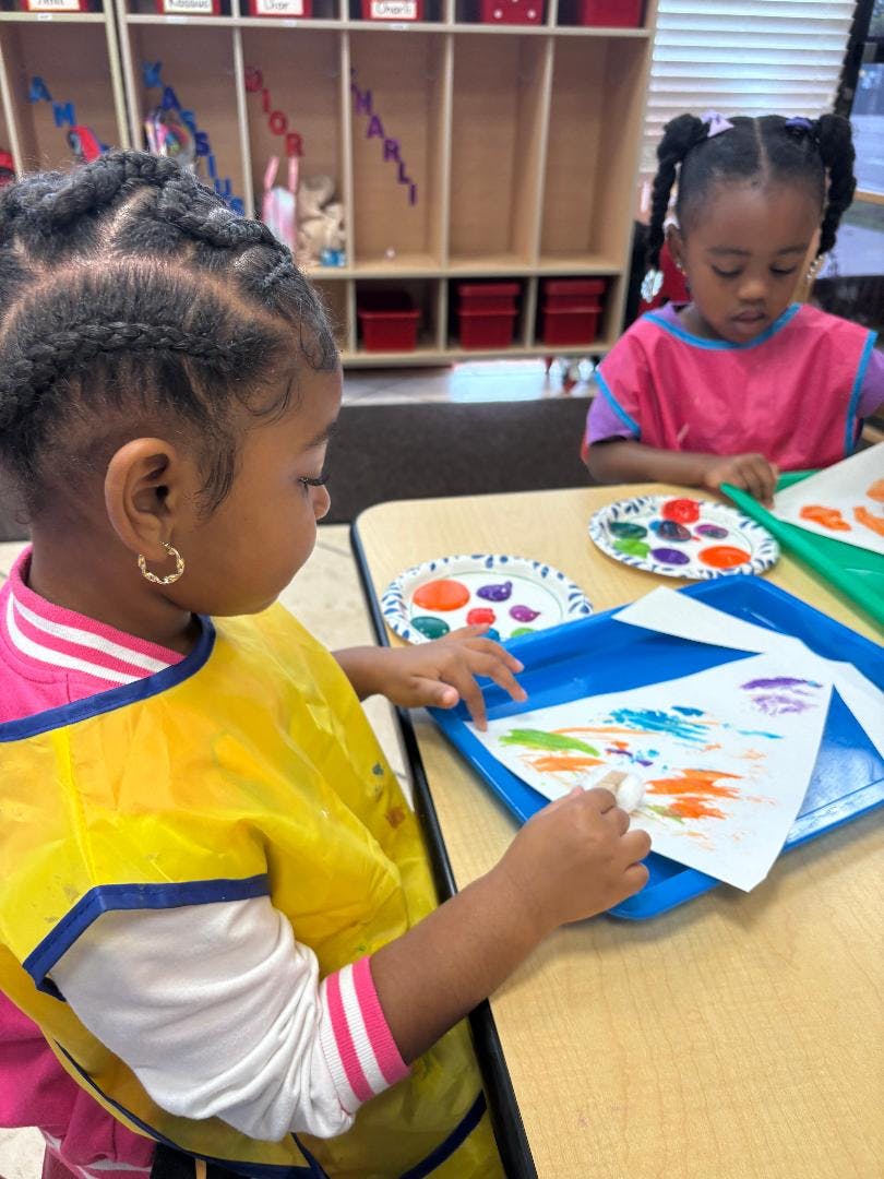 Two children painting at a table in a classroom