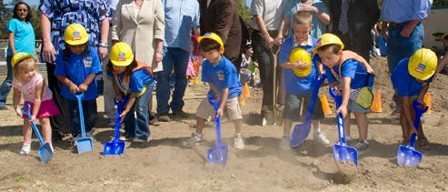 Children in hard hats digging with shovels
