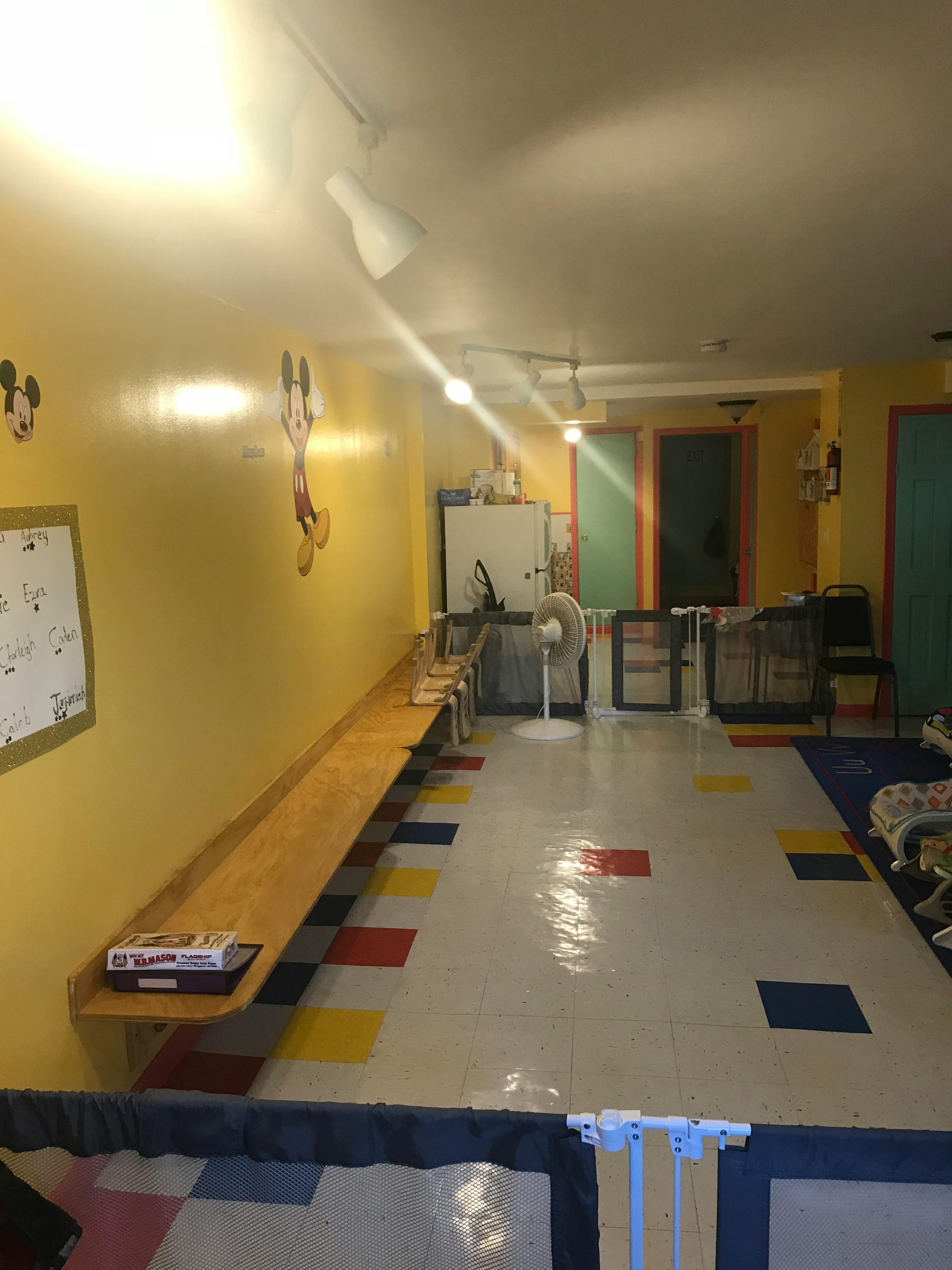 Room with yellow walls, a long wooden shelf, and colorful floor tiles