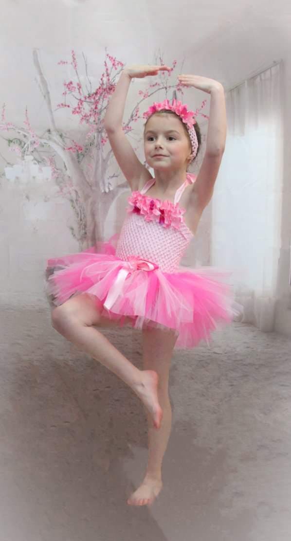 Child in pink tutu and headband posing like a ballerina