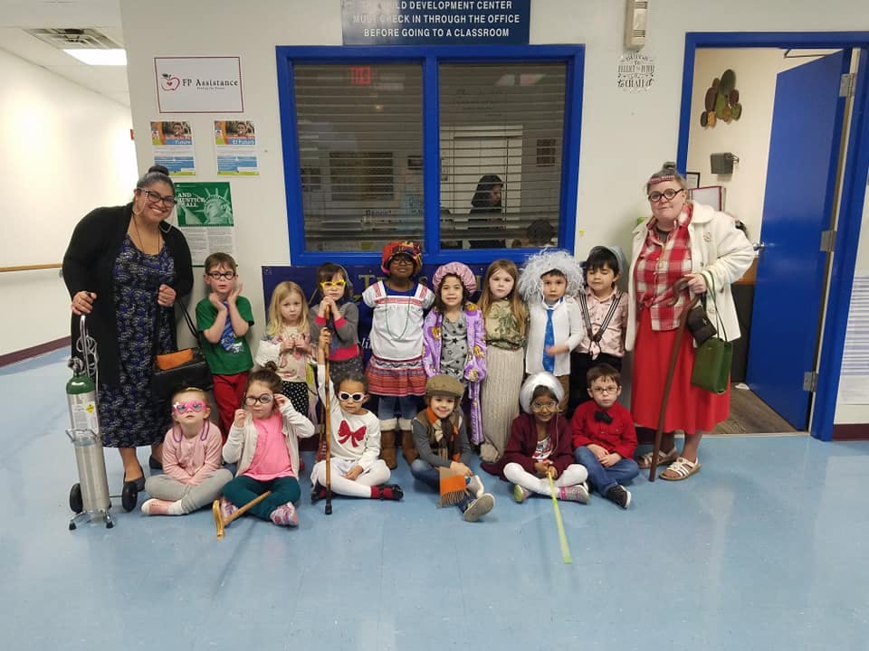 Two adults and multiple children in costumes posing for a photo