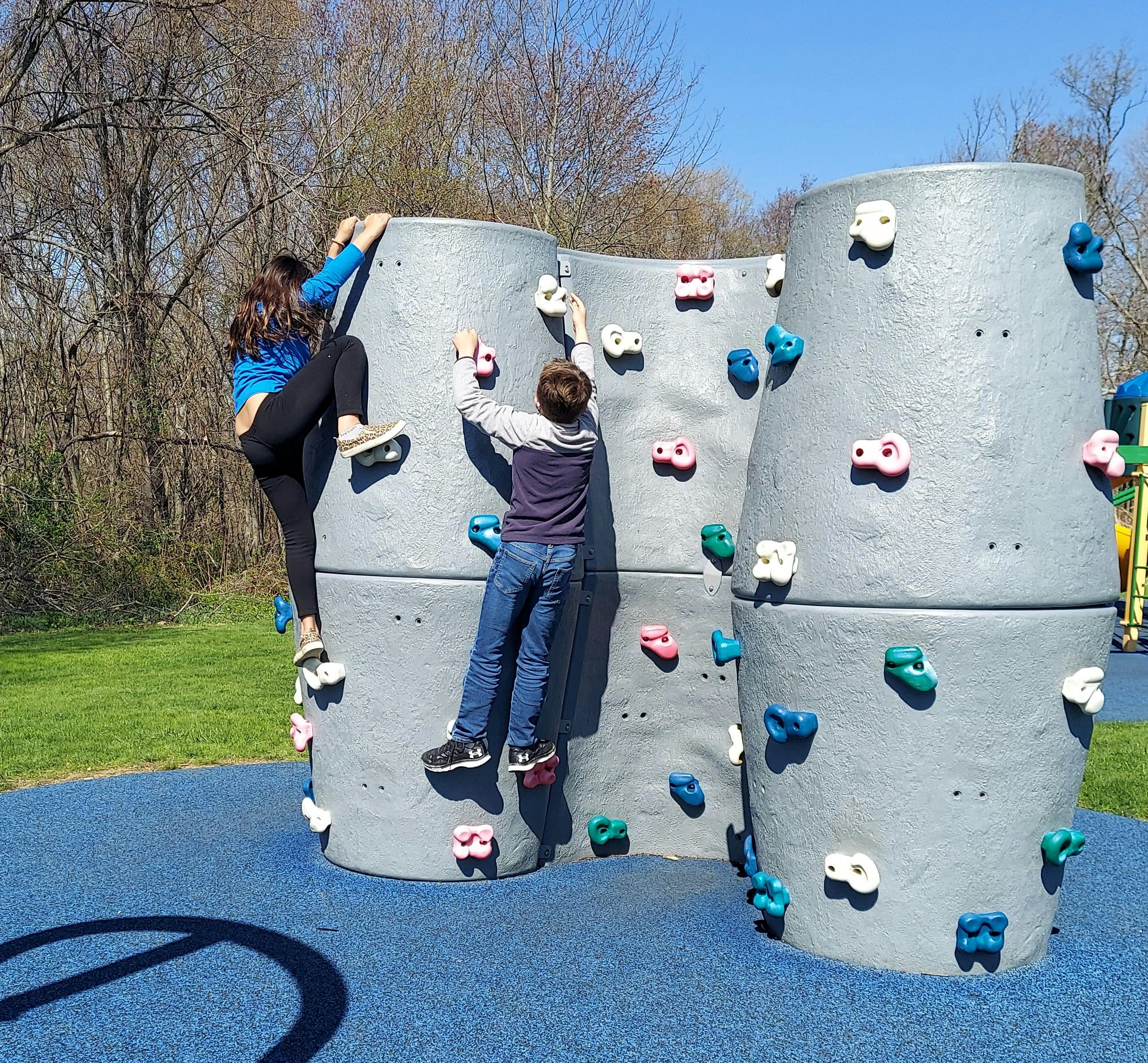 Two children climbing on a rock wall structure