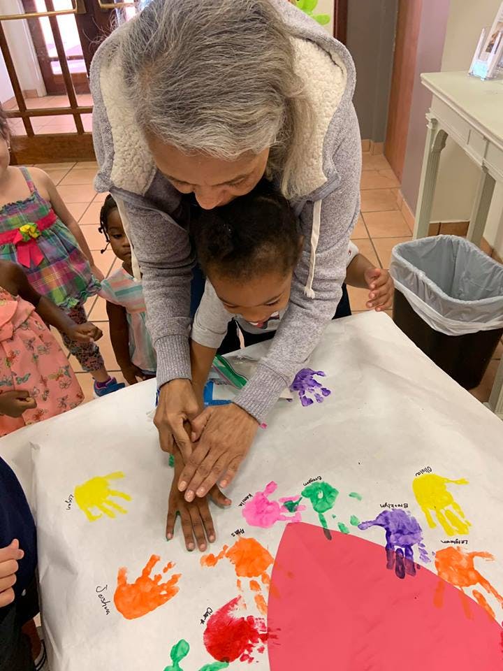 Person helping a child make a handprint on paper