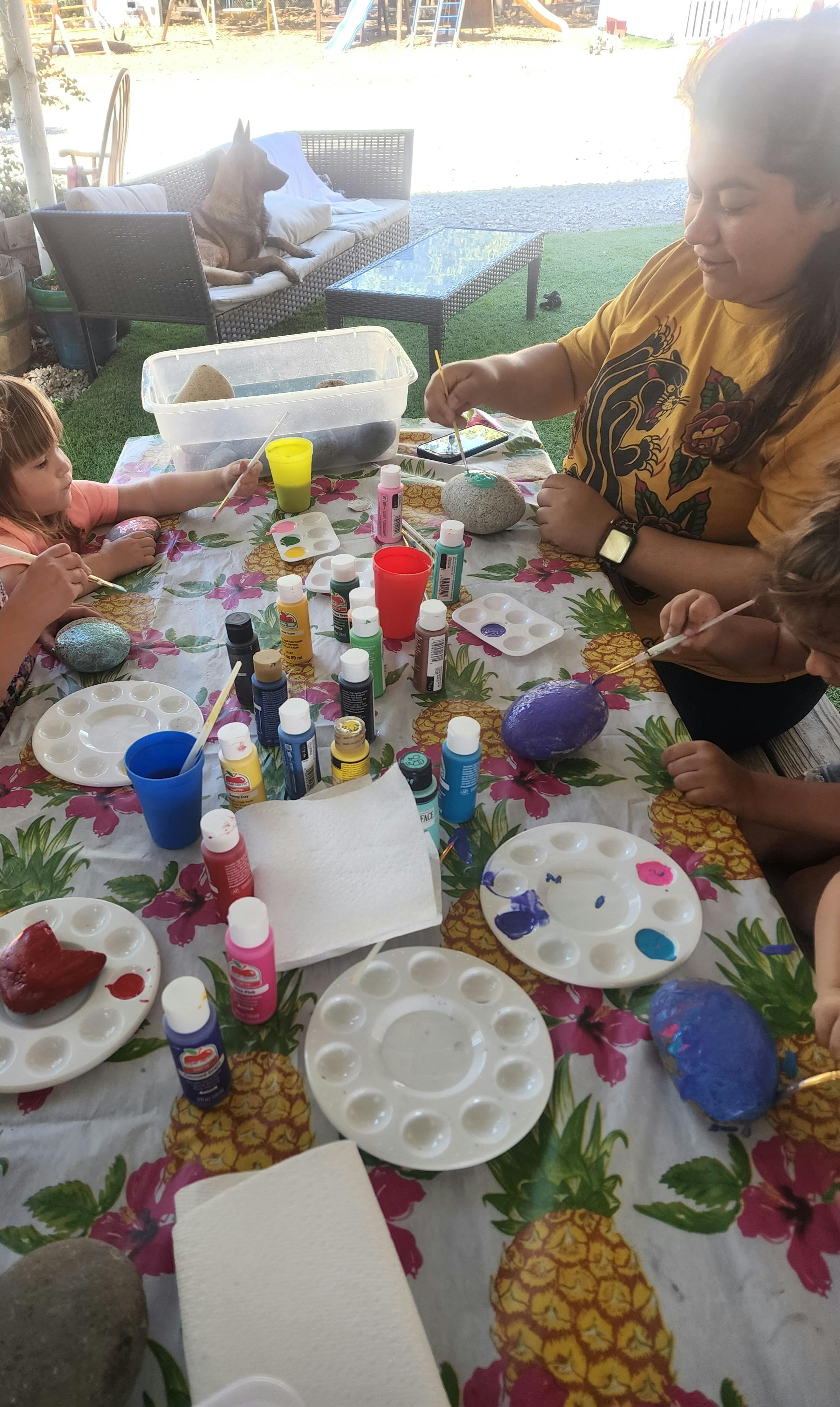 People painting rocks at a table outdoors