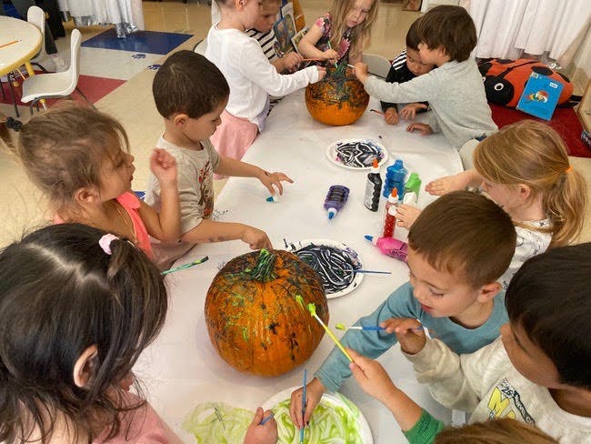 Children painting pumpkins at a table