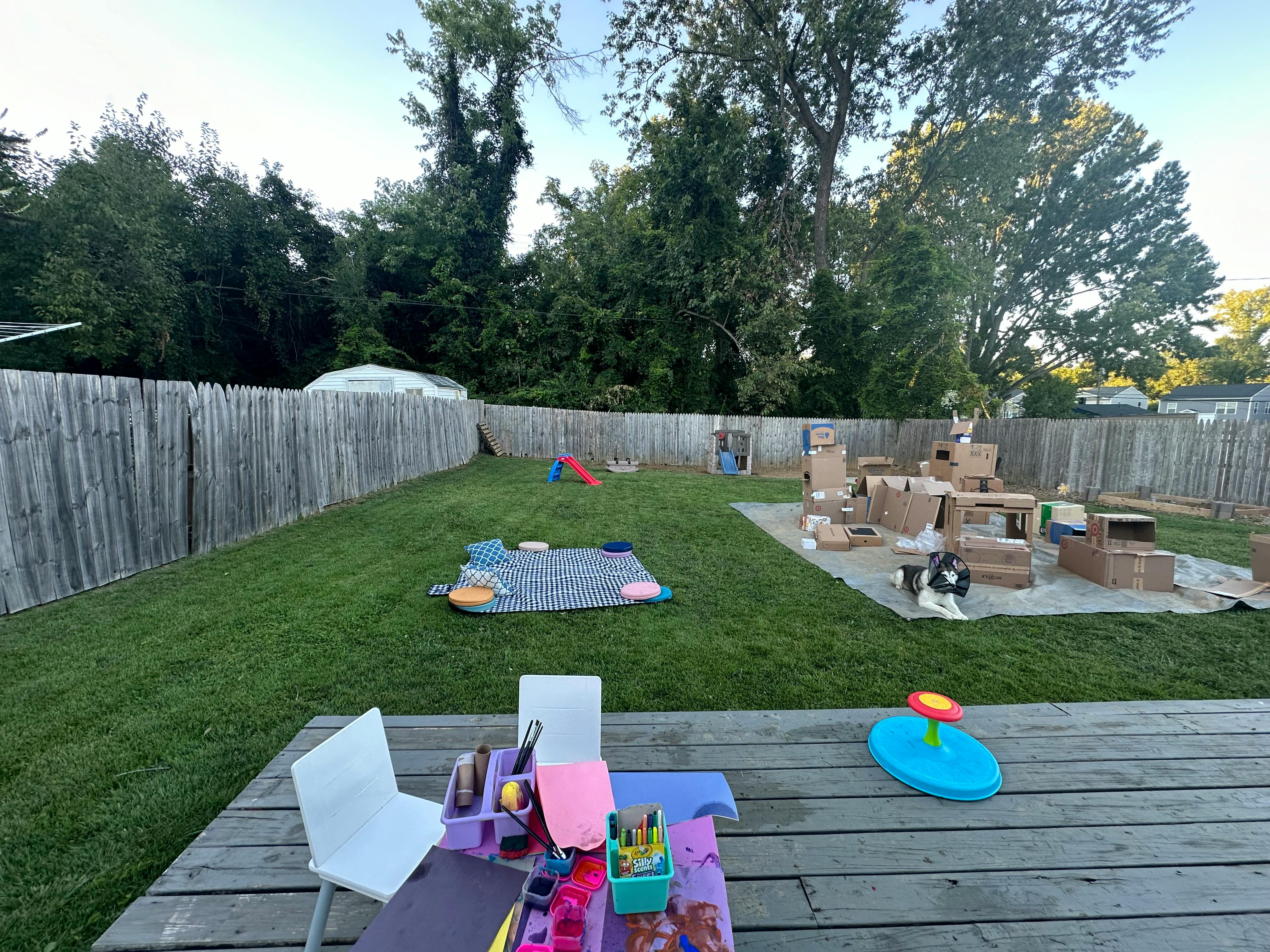 Backyard with a wooden fence, grass, and various play items