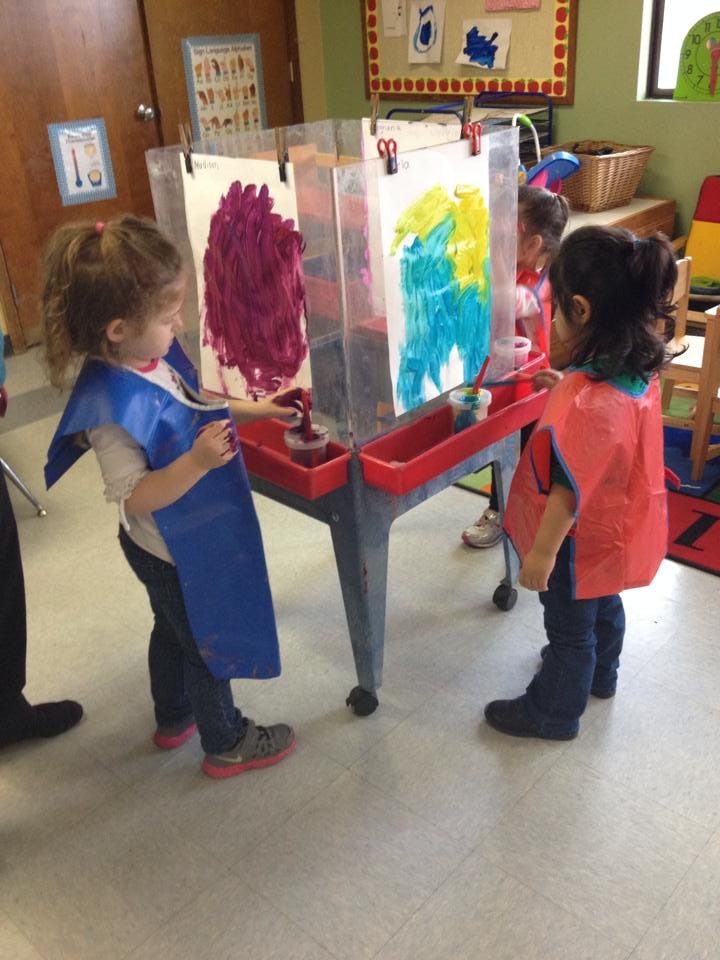 Two children painting at an easel in a classroom