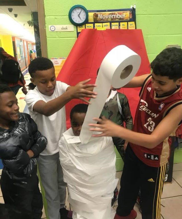 Children wrapping a child in toilet paper