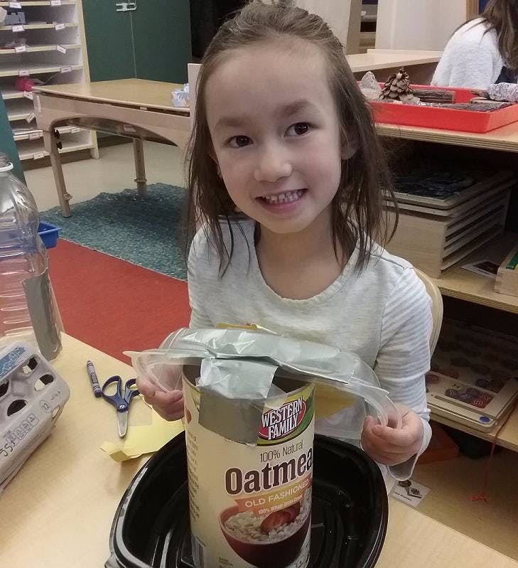 Child holding a plastic bag over an oatmeal container