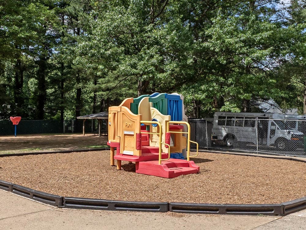 A small outdoor playground with a colorful plastic play structure on wood chips