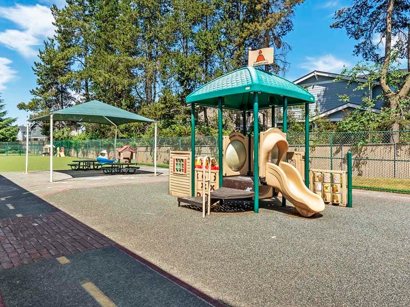 Outdoor playground with slides, play structures, and shaded picnic tables
