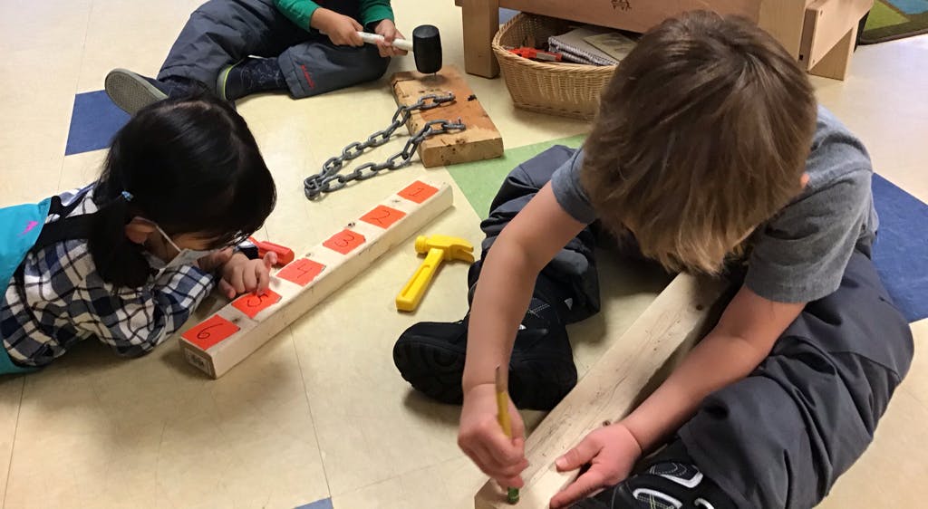 Children playing with wooden blocks and tools on the floor