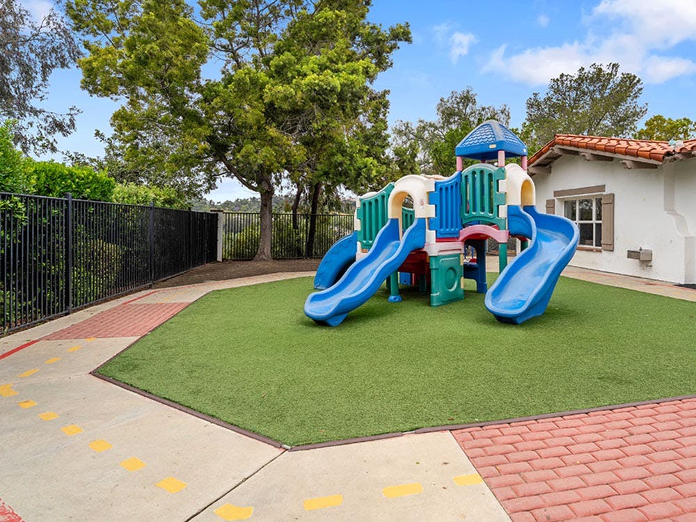 A colorful playground set with slides on artificial turf