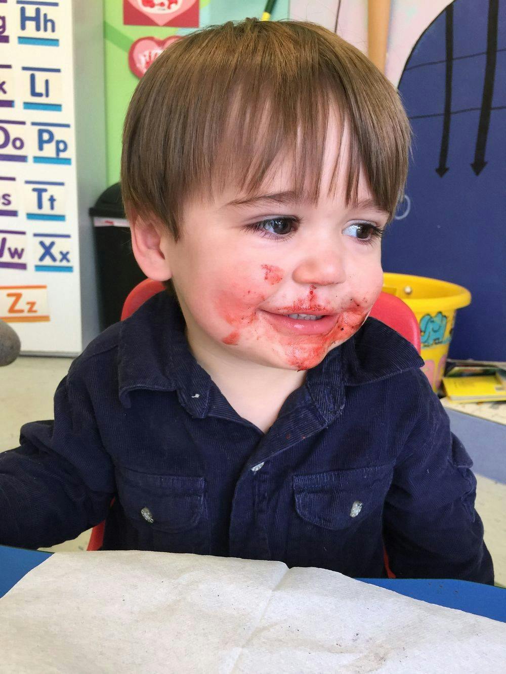Child with red food smeared on face