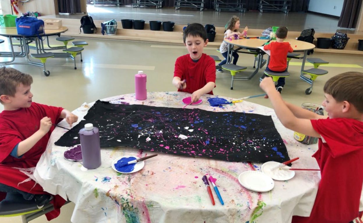 Three children painting on a table