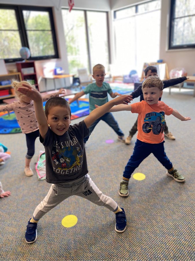 Children in a classroom stretching with arms outstretched