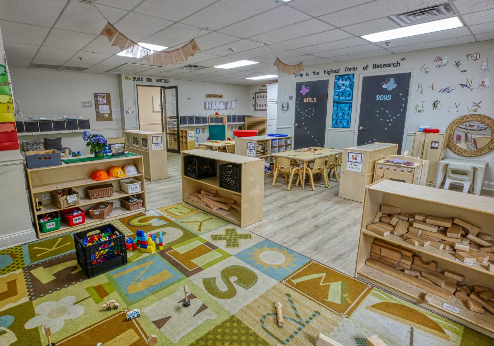 A colorful classroom with play areas, tables, chairs, and shelves of toys