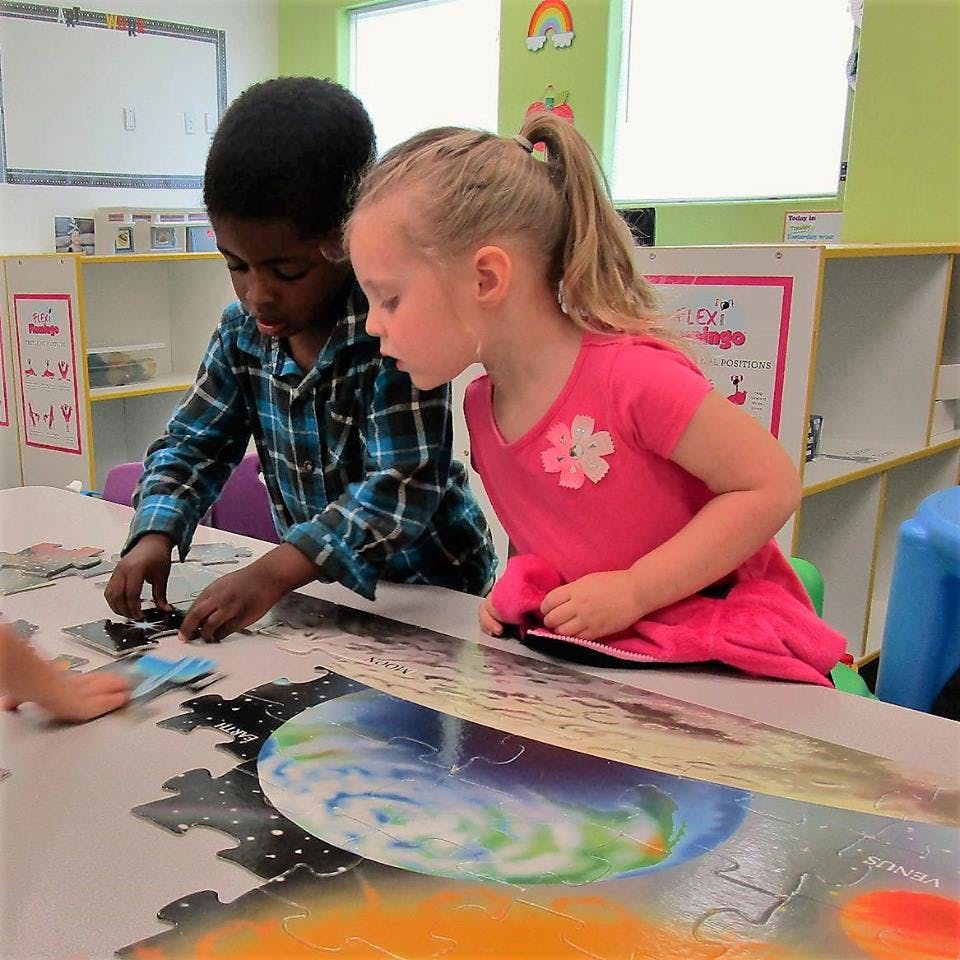 Two children working on a puzzle in a classroom