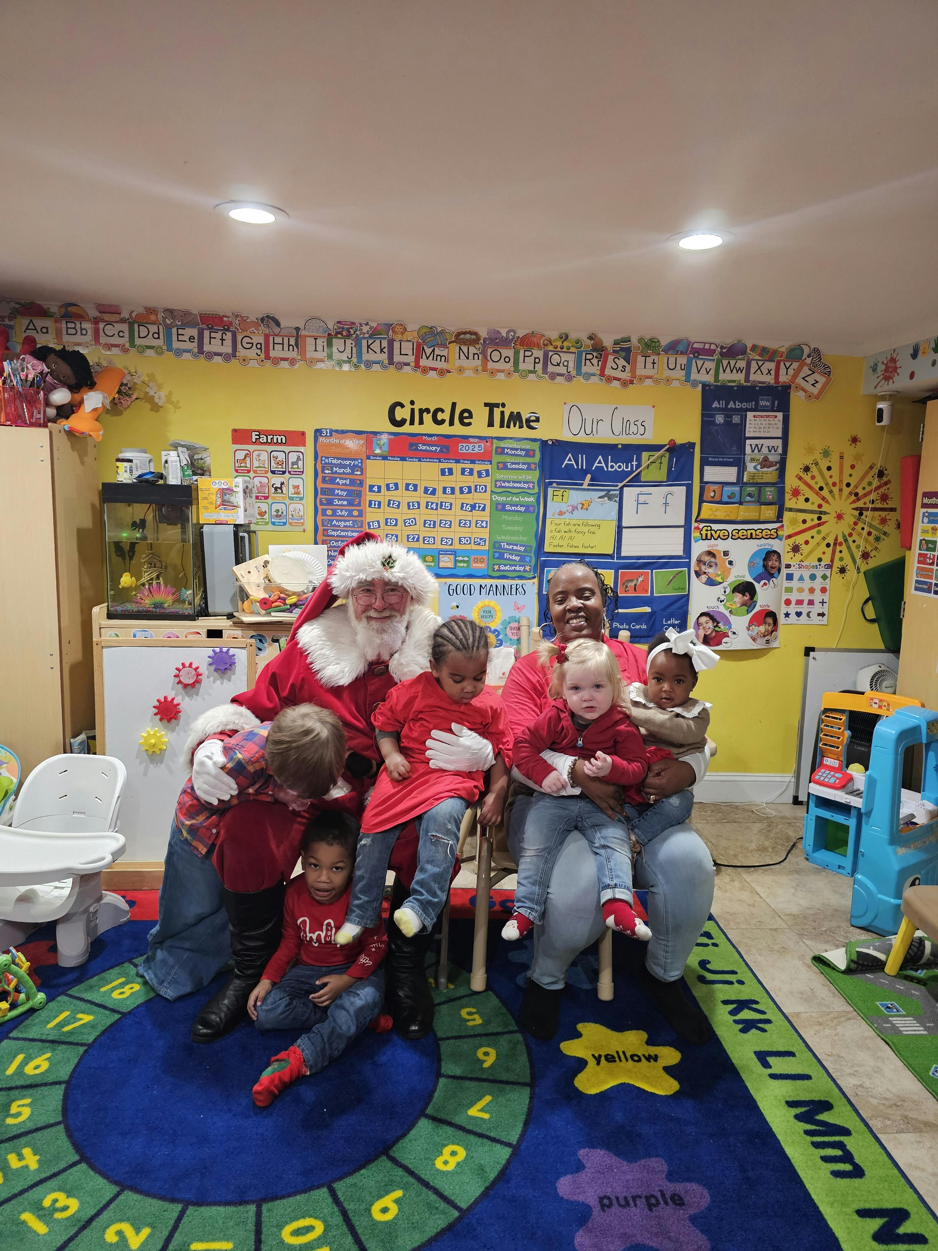 Santa holding several children and a person in a classroom