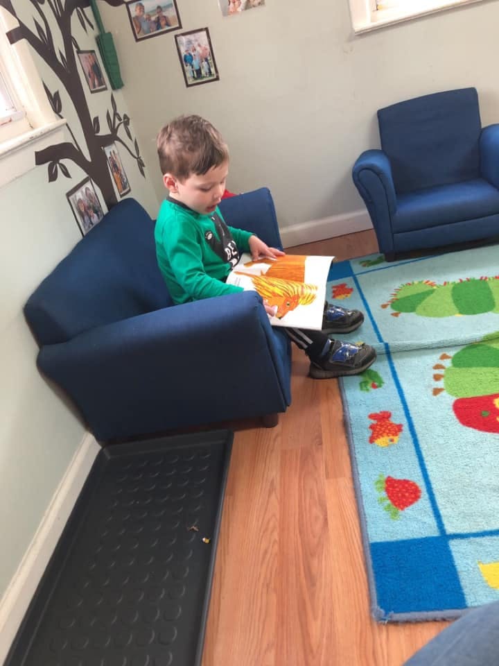 Child sitting in a blue chair reading a book