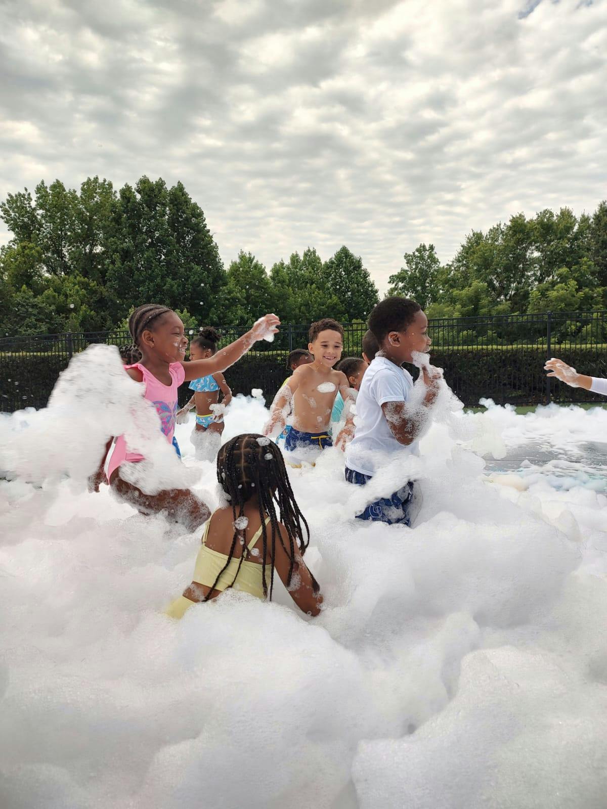 Children playing in a large pile of white foam outdoors