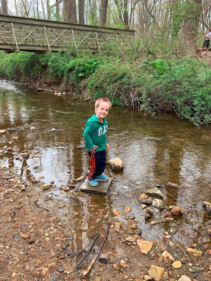 Child standing on a stepping stone in a shallow stream