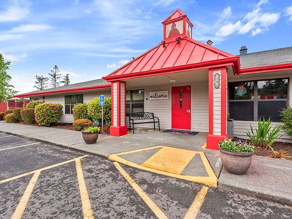 building with a red roof and red door with a welcome sign