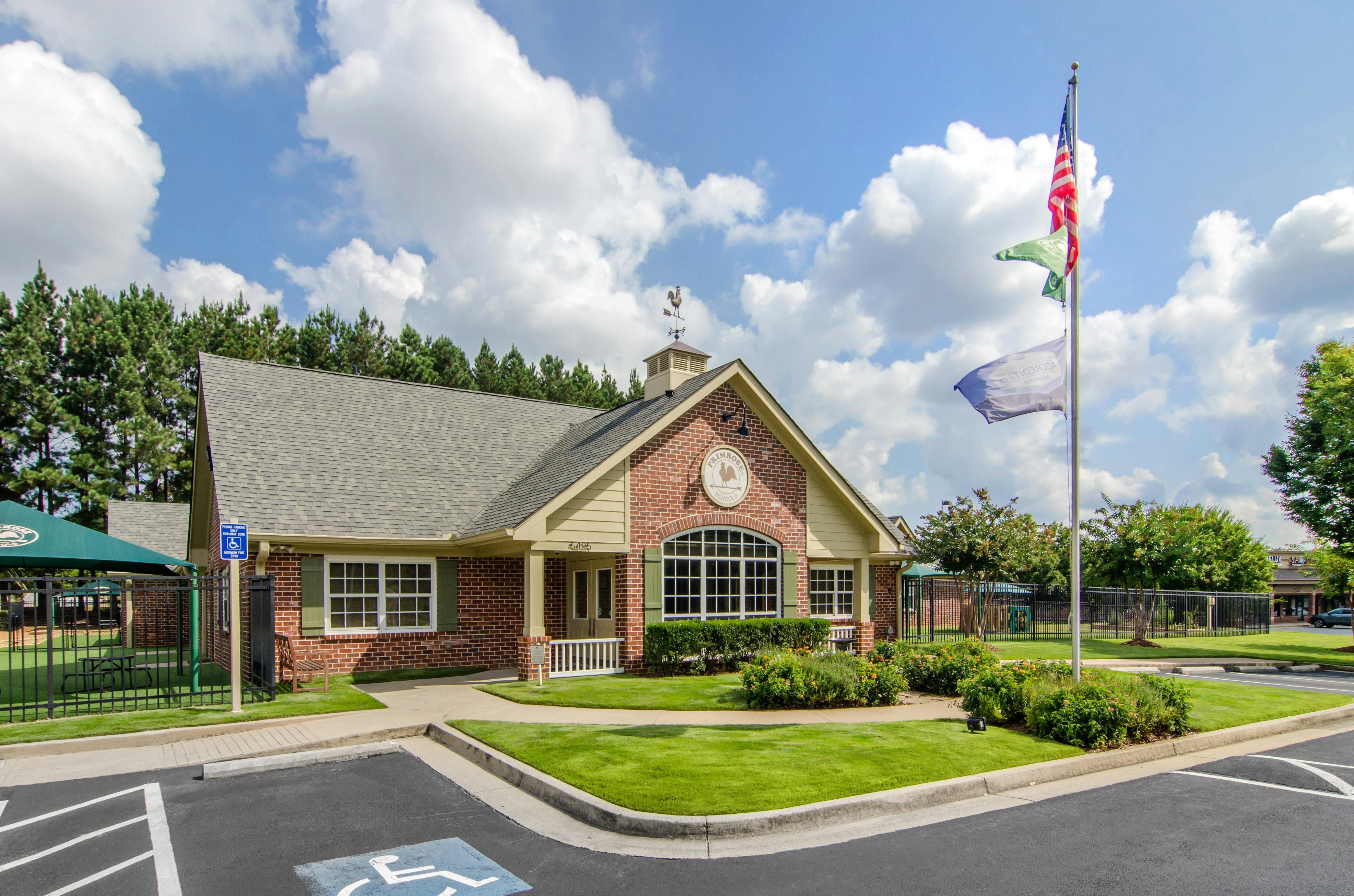 Brick building with a gray roof and weather vane, flags flying from a pole