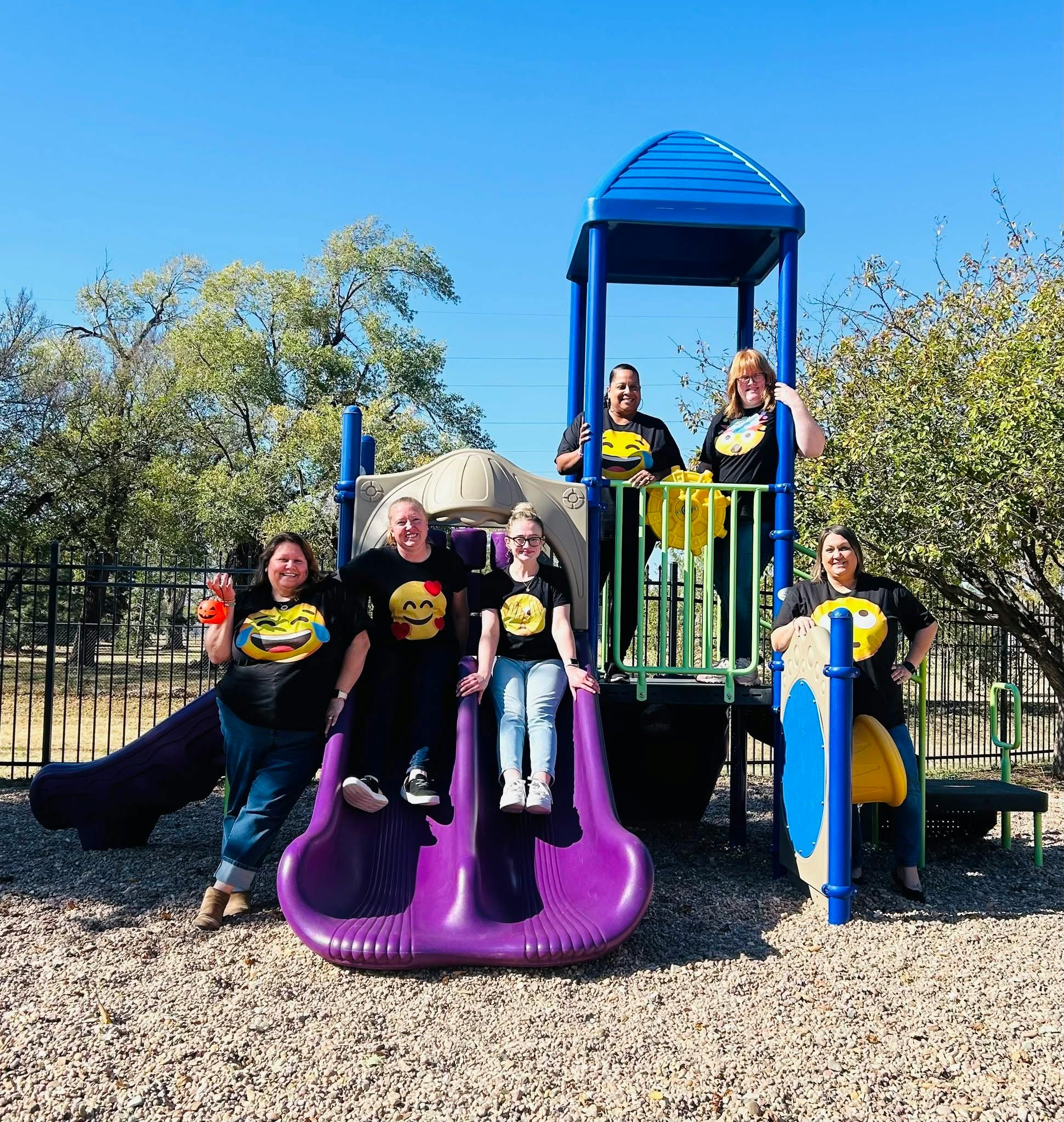 People in emoji t-shirts gathered on a playground structure