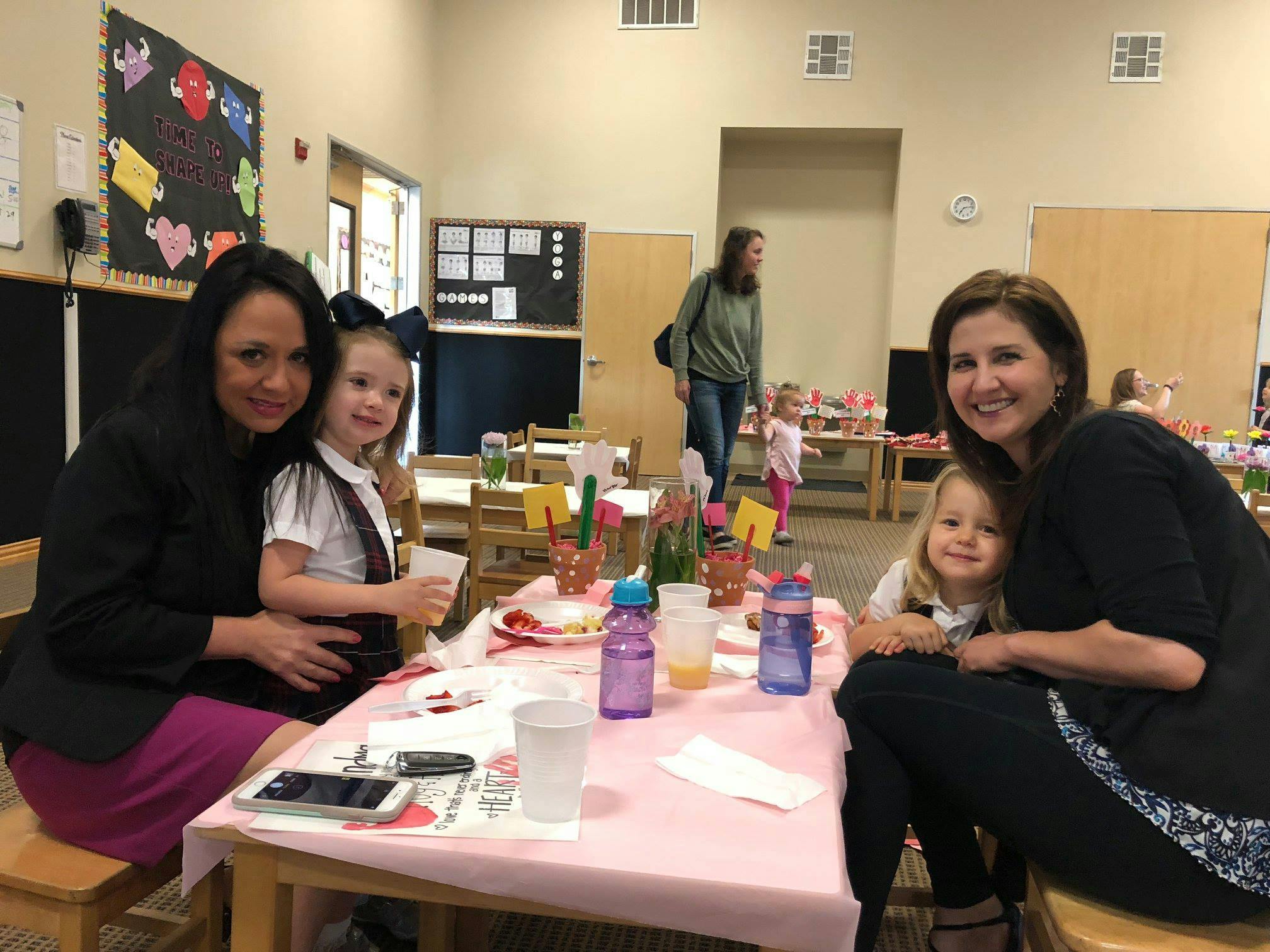 Two women and two children sitting at a table in a classroom