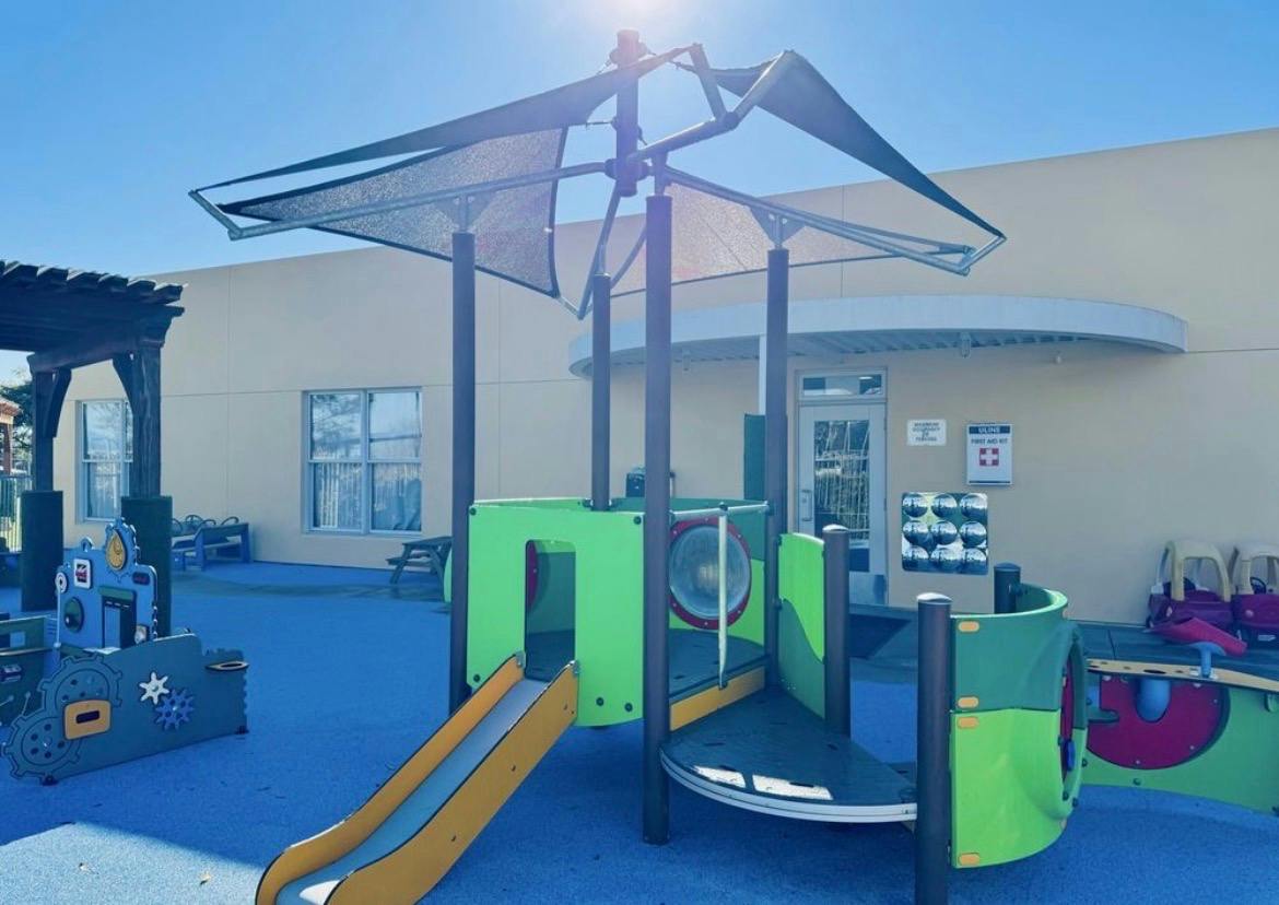 Playground equipment with a slide and shade canopy on a blue ground surface