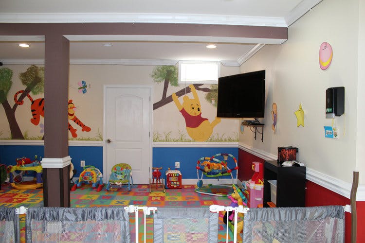 Playroom with colorful floor mats, toys, and Winnie the Pooh wall murals