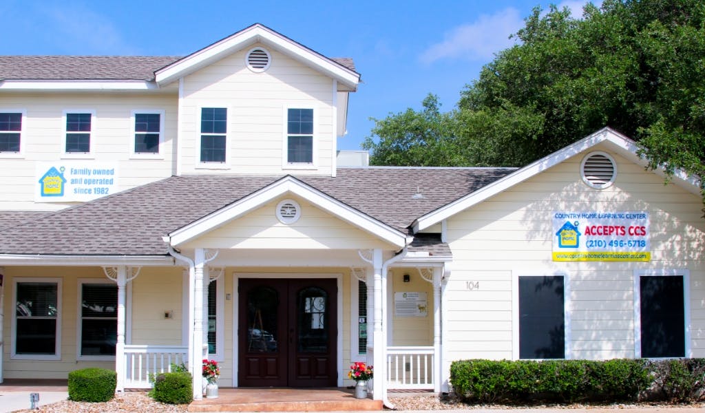 Exterior of a light-colored building with multiple gables and a porch