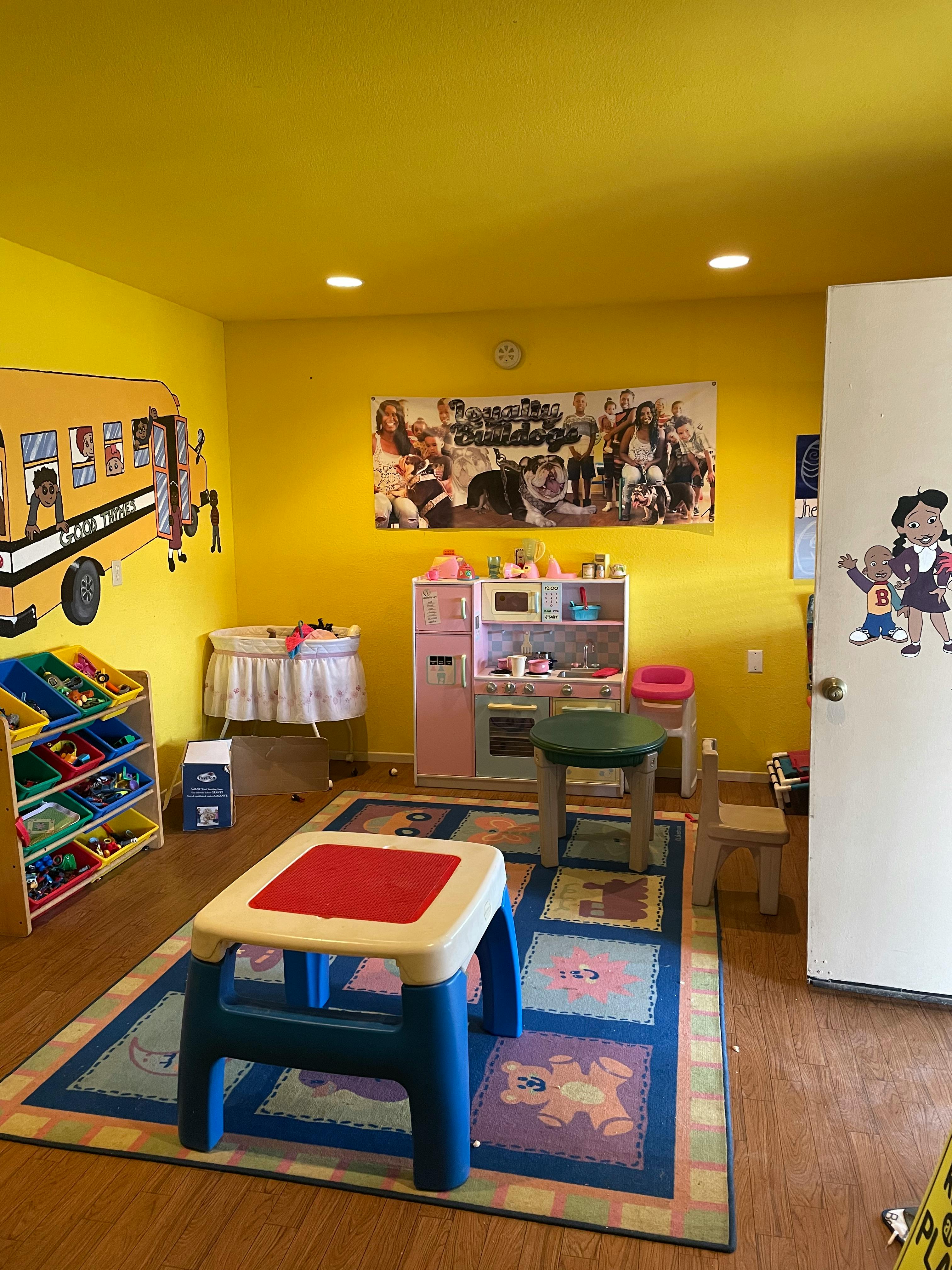 Playroom with yellow walls, toy kitchen, and small tables