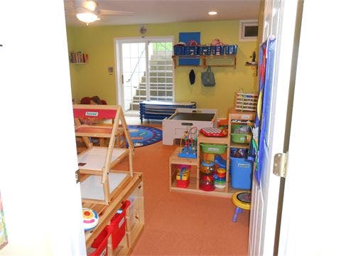 Playroom with toys, shelves, and a rug