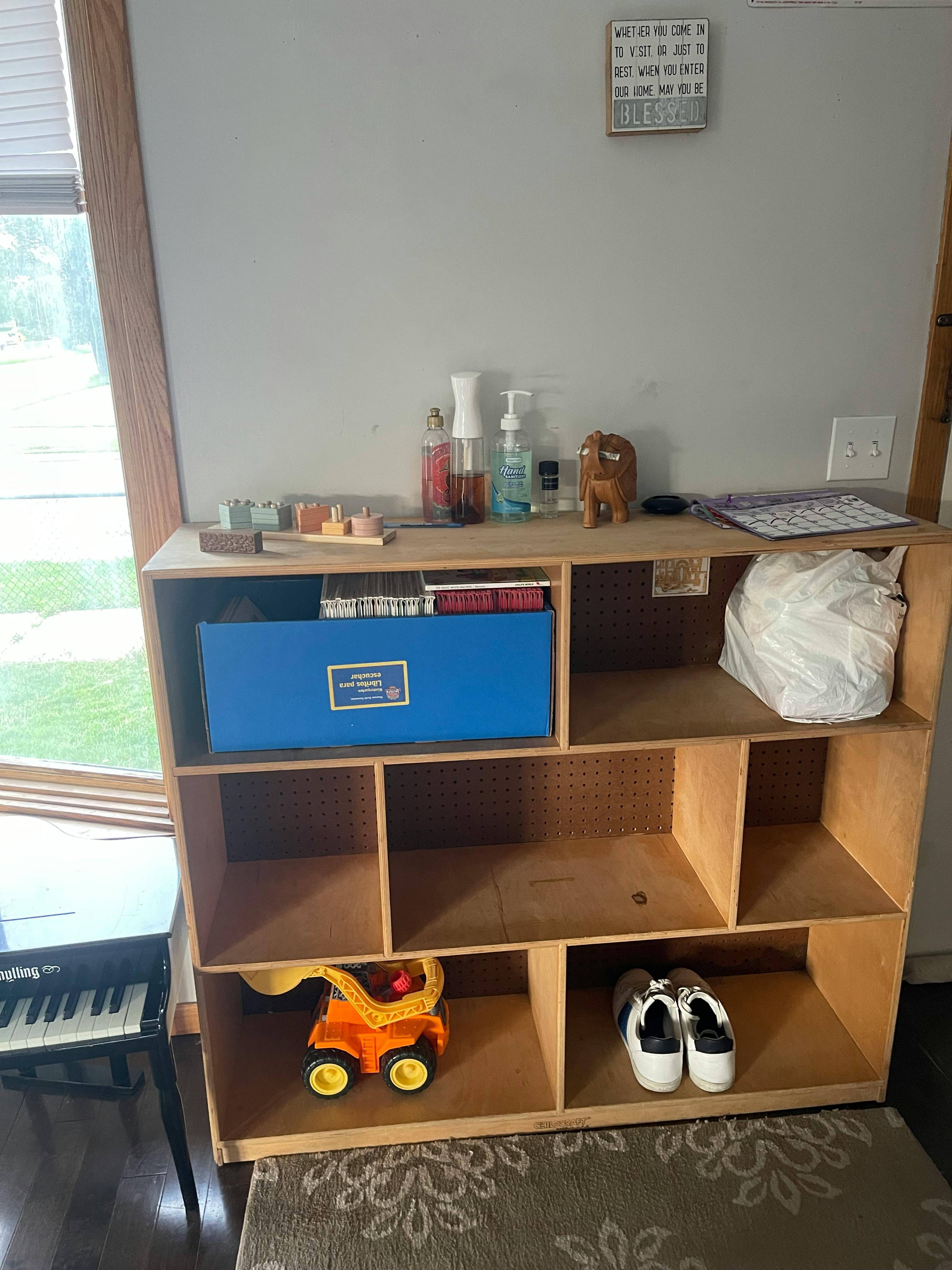 Wooden shelving unit with various items including a blue box, toy truck, and shoes