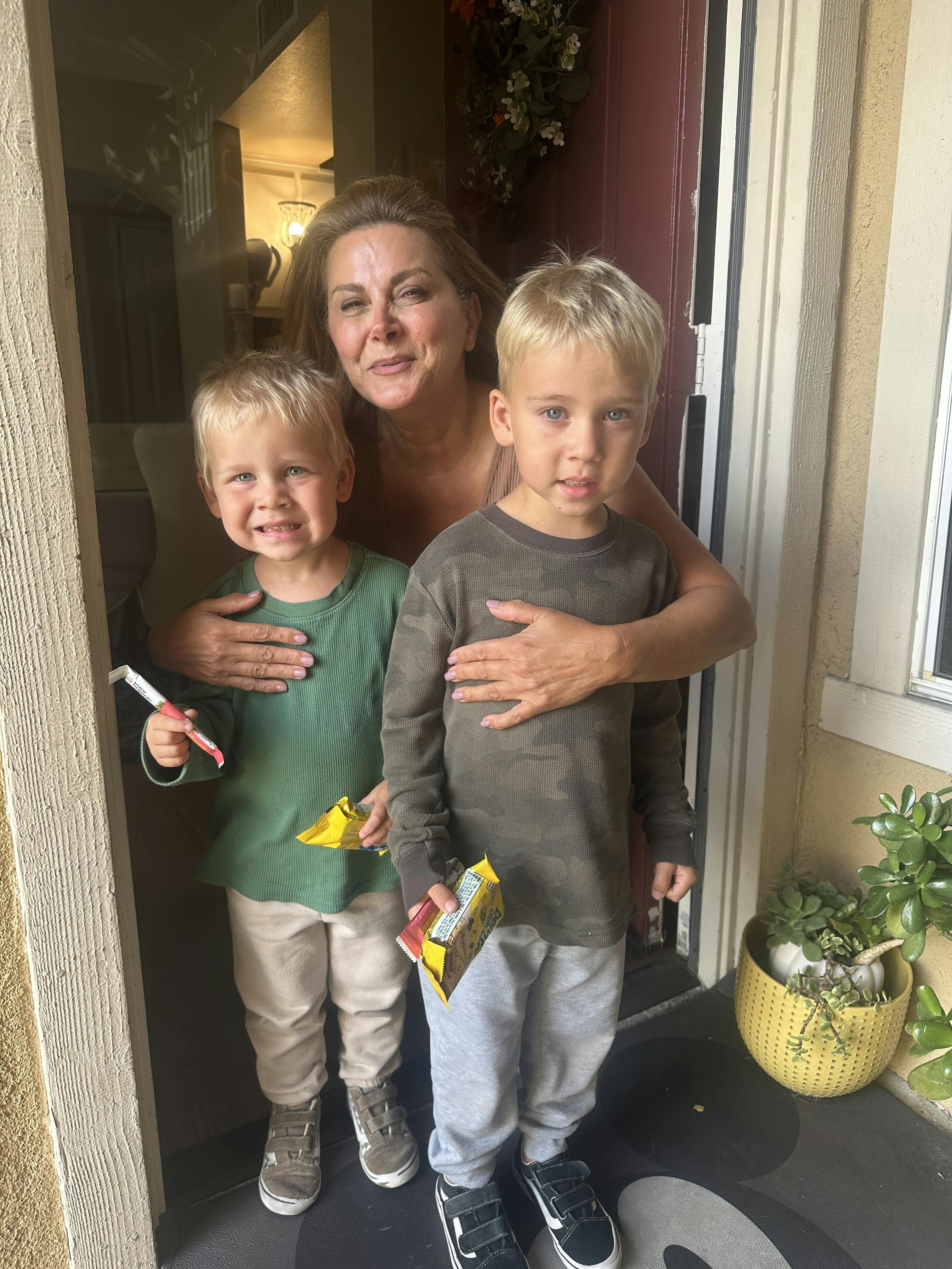 A person standing in a doorway with their arms around two children
