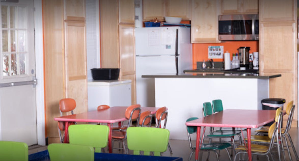 Small tables and chairs in a room with a kitchen area