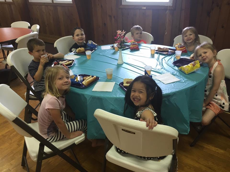 Group of children sitting around a table with food