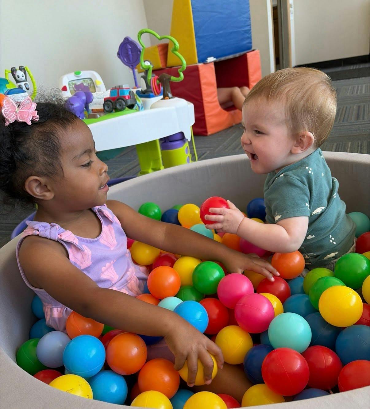 Two children playing together inside a ball pit