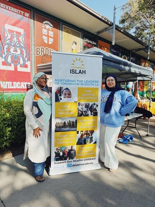 Two people standing next to an Islah Academy banner with text about education